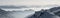 Snow Mountains Panorama in low lying inversion valley fog. Silhouettes of foggy Mountains. Scenic snowy winter landscape