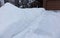 Snow is Piled High Besides a Driveway in Winter