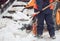 Snow removal in the city. Worker helps shovel snowplow.