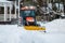 A snow removal tractor cleans the area in the park. Municipal service cleaning sidewalk from snow