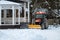 A snow removal tractor cleans the area in the park. Municipal service cleaning sidewalk from snow