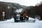 The snow-removing machine cleans the road from the snow in the background of the mountain taiga.