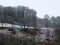 Snow scene with ice on frozen forest trees and hillside fields with a stone wall bordering a country lane