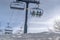 Snow and skiers on ski lifts against bright sky