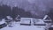 Snow slowly falling on traditional mountain village at dawn