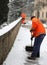 Snow spreader with high visibility jacket shovels the sidewalks