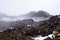 Snow storm building up over lava fields on the slopes of Mt Ruapehu. Mountain range disappearing in thick fog. Tongariro