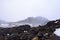 Snow storm building up over lava fields on the slopes of Mt Ruapehu. Patches of snow over Whakapapa Ski Field, Tongariro