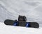 Snowboard and black backpack on snow in high winter mountains