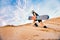 Snowboarder climbs to top of sand dune for snowboarding