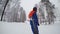 A snowboarder descends from a mountain along a winter forest with a skier in the background