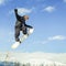 Snowboarder doing high jump above the mountain