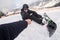 Snowboarder fastens snowboard buckles sitting on the top of snow hill and give five