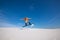 Snowboarder is flying over the sand dune.