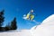 Snowboarder free rider jumping in air downhill on copy space background of blue sky and white snow.