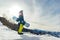 Snowboarder freerider in funny hat in the mountains is preparing to descend on the background of snowy mountains