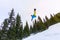 Snowboarder freerider jumping from a snow ramp in the sun on a background of forest and mountains