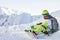 Snowboarder freerider sits on a slope and fastens his snowboard while looking at the mountains. Russia Sochi Rosa Khutor