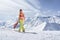 Snowboarder girl in a swimsuit walking on top of mountain