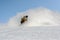 Snowboarder glides on mountain and raises up snow