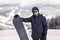 Snowboarder hold snowboard on top of hill close up portrait, snow mountains snowboarding on slopes. Ski resort.