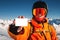 snowboarder holds an empty lift pass with a mountain in the background. A young man is holding an empty ski pass and