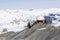 Snowboarder in orange ski goggles in a white helmet climbs to the top and extends a helping hand in the Alps mountains. On the