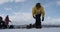 The snowboarder puts the board on his feet while standing