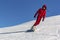 Snowboarder quickly rolls down the mountain in loose snow against a blue sky on a sunny day.