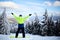 Snowboarder raised his arms and hands to the sky at ski resort. Man climbed a mountain top through forest for