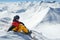 Snowboarder sits high in mountains on the edge of slope