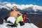 Snowboarder sitting topless at the snowy mountaintop and sunbathing.