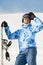 Snowboarder in ski suit stands with snowboard