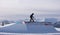 Snowboarder sliding a rail with mountains in the background