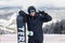 Snowboarder with snowboard portrait with victory sign on the top of mountains hill before ride