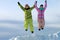 Snowboarders friends in bright vivid clothes jumping