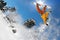 Snowboarders jumping against blue sky