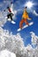 Snowboarders jumping against blue sky