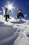 Snowboarders jumping against sun