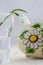 Snowdrop flower in vase, white easter egg with painted daisy flower