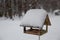 Snowfall in the city. Snow-covered bird feeder on a tree in the