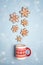 Snowfall from gingerbread snowflakes in Christmas mug on blue ba