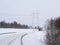 Snowfall on highway. Far away approaching truck and high voltage power pole