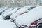 Snowfall and snow-covered cars stand in the courtyard of a multi-storey building.