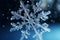 Snowflake closeup isolated on winter snow blue background. Copy space. Ice crystal. Frozen water in snowflake shape. Winter