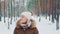 Snowing in forest: woman in winter clothes walking and admiring the nature