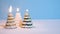 Snowing on Golden, white and green Christmas tree wax candle burning on blue background New Year or Christmas video