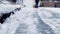 Snowing weather conditions, unrecognisable man using snow removal machine to clean the sidewalk in winter