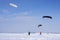Snowkiters ride on a winter clear day through the snowy plain