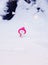 snowman in a bright pink hat sitting in a white snowdrift with a gift in the winter new year`s Park